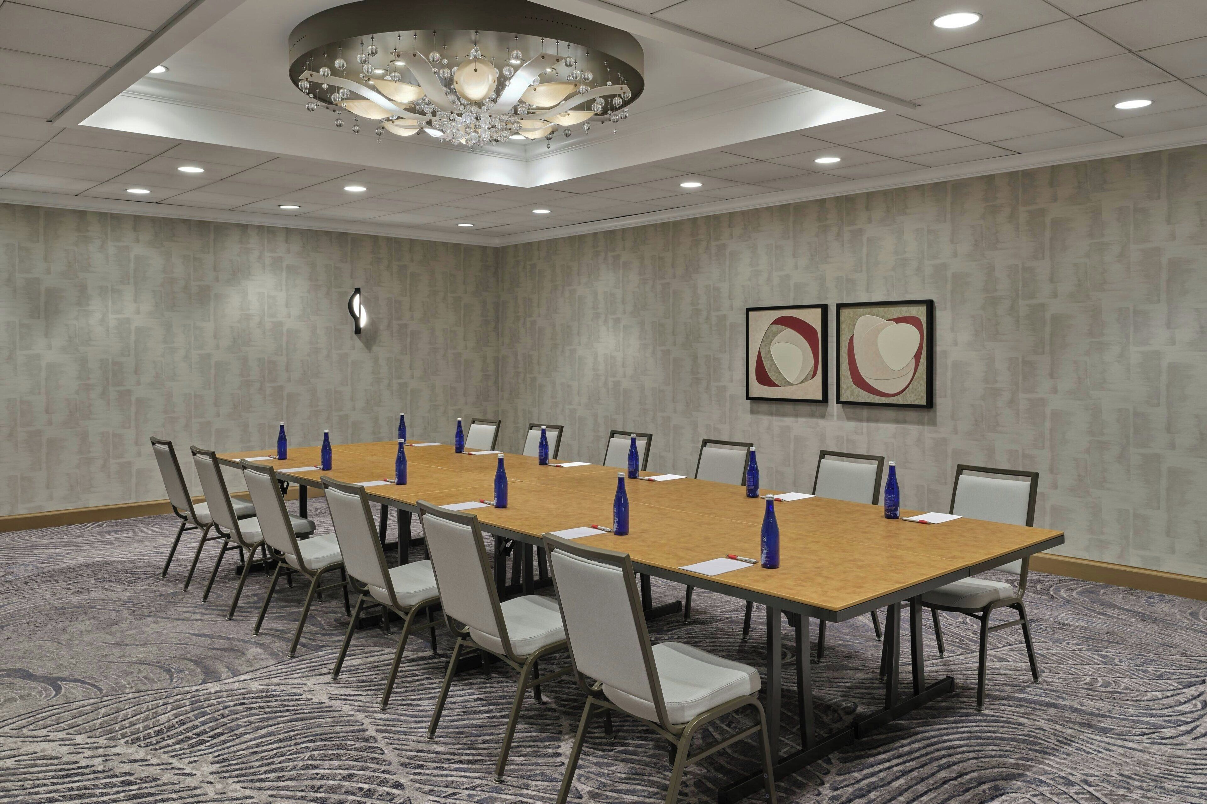 Une salle de conférence avec une longue table, des chaises et un lustre.