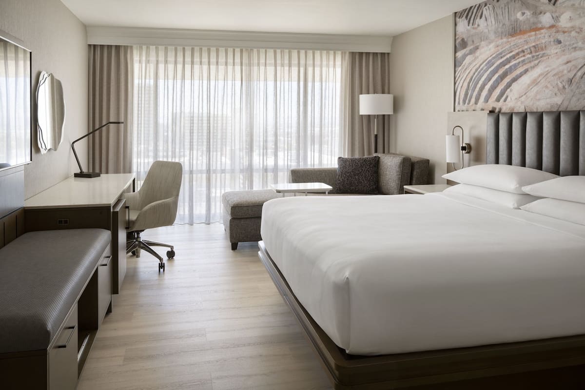 Quarto de hotel com uma cama grande, uma escrivaninha, uma cadeira e um sofá.