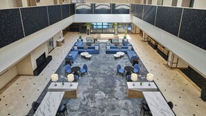 A spacious lobby with a central seating area, multiple tables, and a view of the outdoors. - Salt Lake Marriott Downtown at City Creek (Salt Lake City)