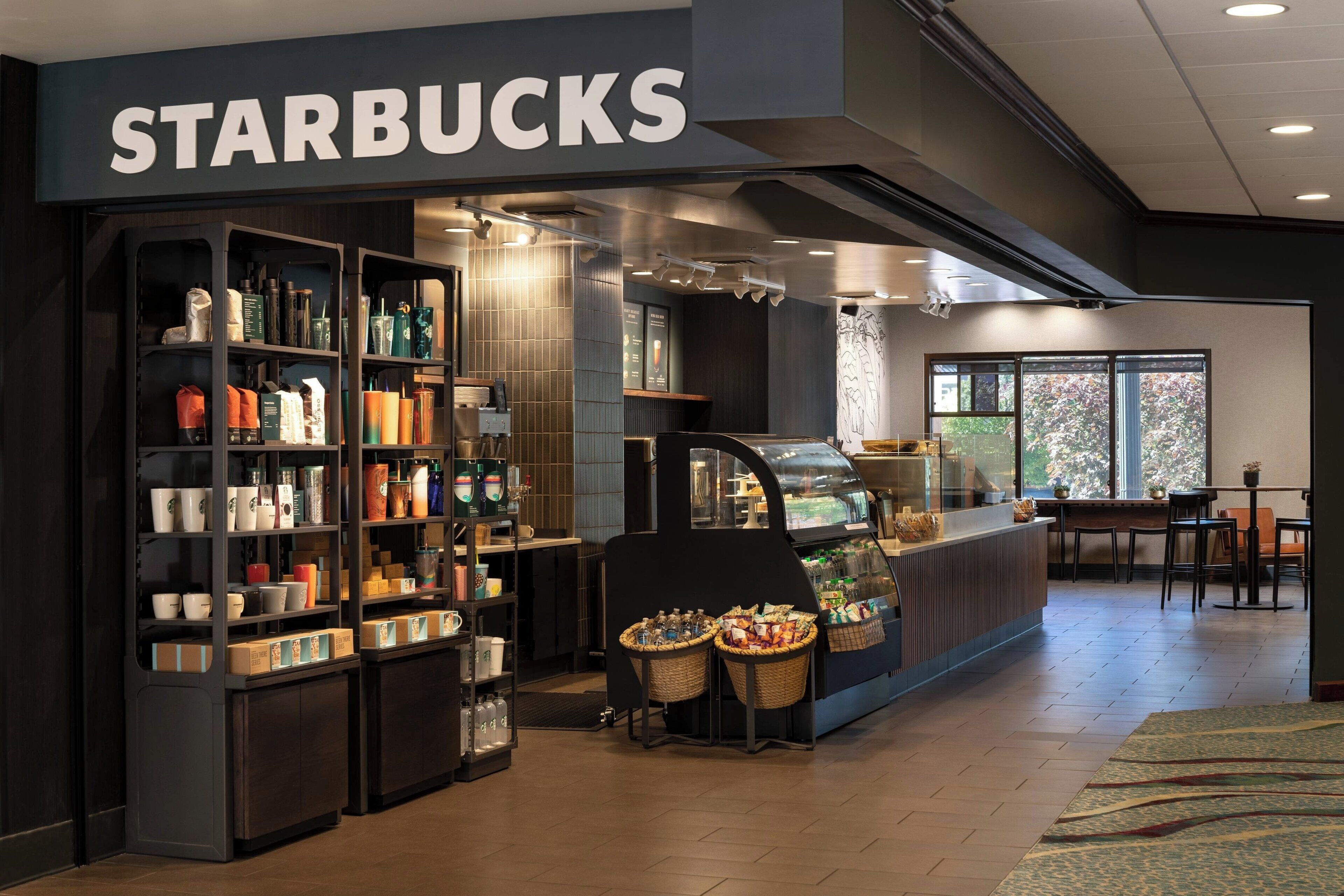 Ein Starbucks Geschäft mit Warenregalen, einer Kaffeebar und einem Sitzbereich.
