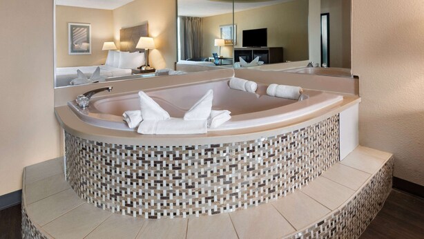 Ein modernes Badezimmer mit einer großen, gewölbten Badewanne, einem Spiegel und einem Fernseher.