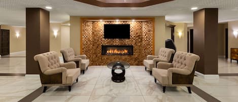 Un hall con chimenea, dos sillones, una mesa de centro y un candelabro.