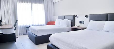Ett hotellrum med två sängar, ett skrivbord, en stol och en luftkonditioneringsanläggning.