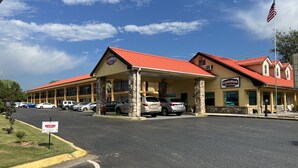 A Country Hearth Inn with a red roof, stone pillars, and a parking lot with several cars. - Country Hearth Inn & Suites Cartersville (Cartersville)