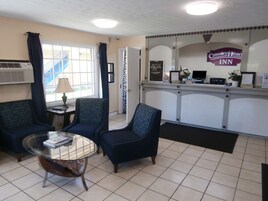 Zona de recepción del Country Heart Inn, con un mostrador de recepción, dos sillones, una mesa de vidrio y una ventana con cortinas.