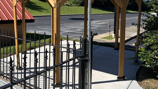 A gazebo with a metal roof and wooden beams, a metal gate, and a parking lot in the background. - Country Hearth Inn & Suites Cartersville (Cartersville)