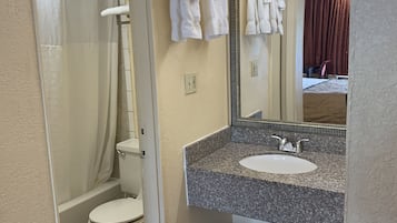 Ein Badezimmer mit Toilette, Waschbecken, Spiegel und Duschbereich.