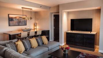 A modern living room with a sofa, coffee table, TV, and dining area.
