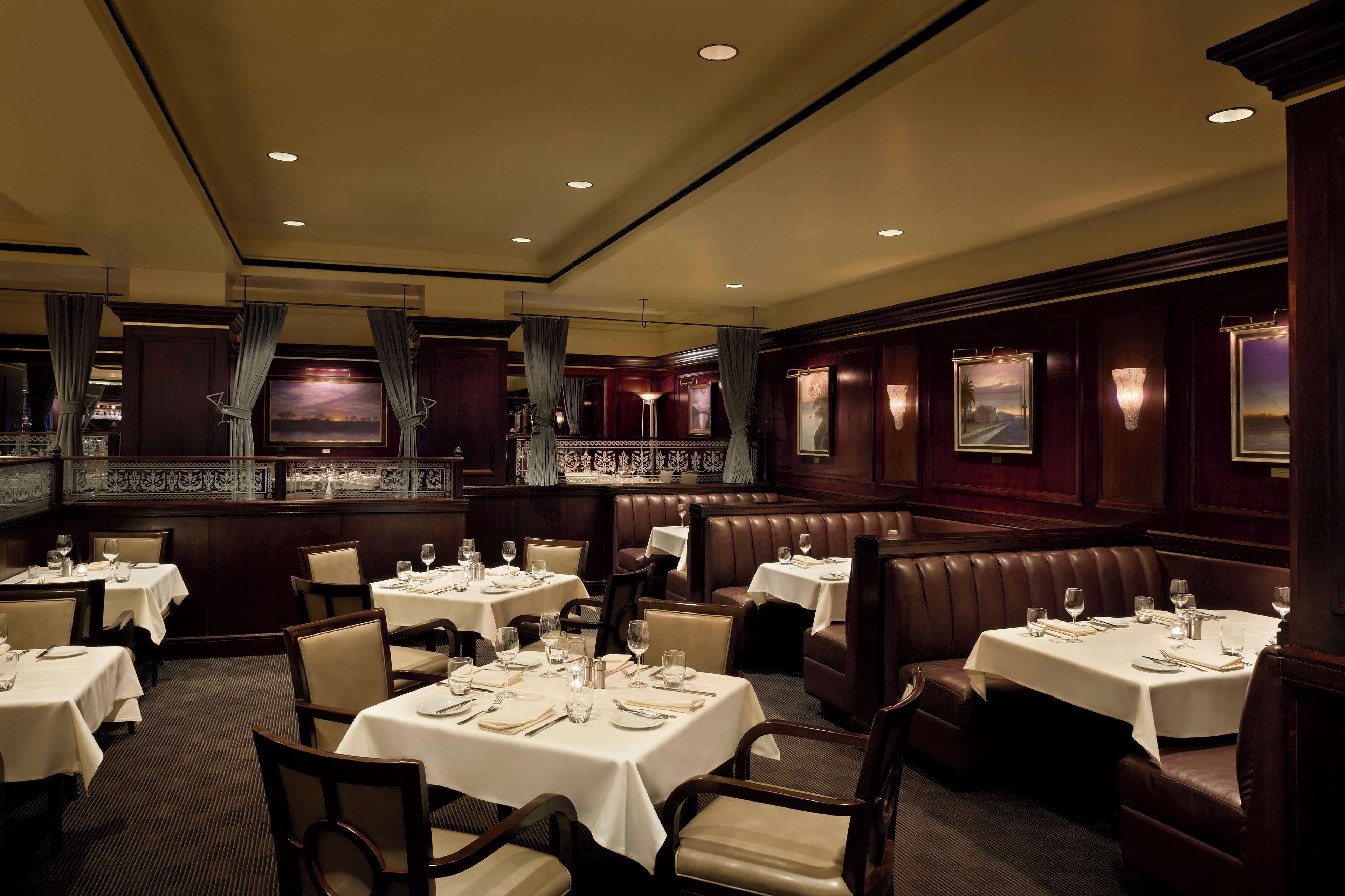 A restaurant with multiple tables and booths, each set with cutlery and glasses.