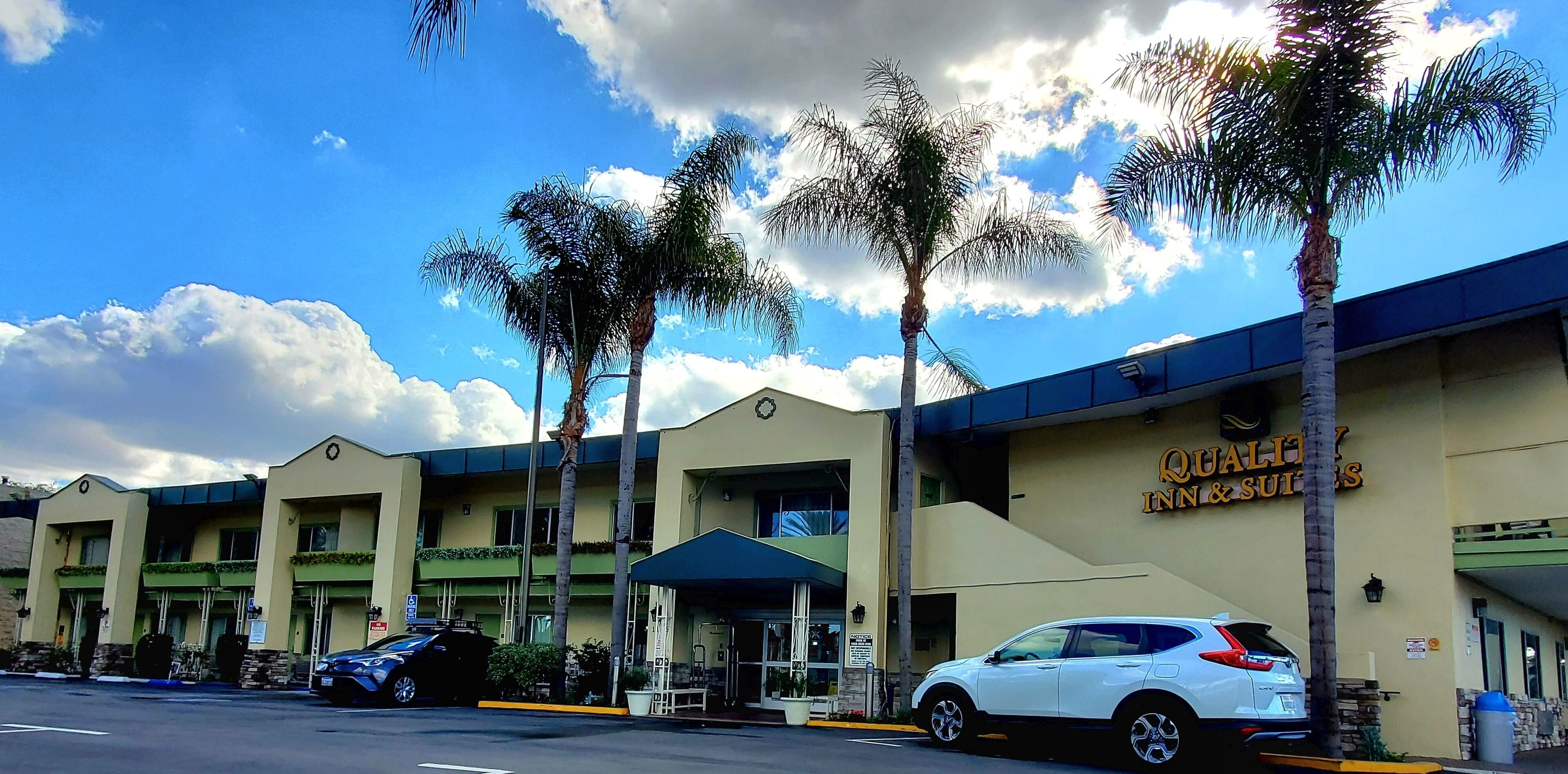 A hotel with a sign reading "Quality Inn & Suites" and a white car parked in front.