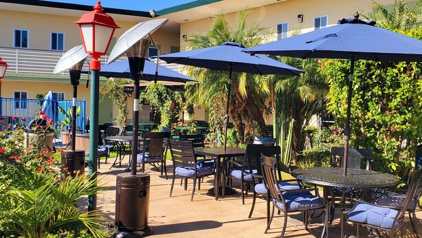 Une terrasse extérieure avec des tables et des chaises, des parasols et un lampadaire.