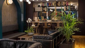 A modern bar area with leather seating, a variety of beverages, and decorative plants.