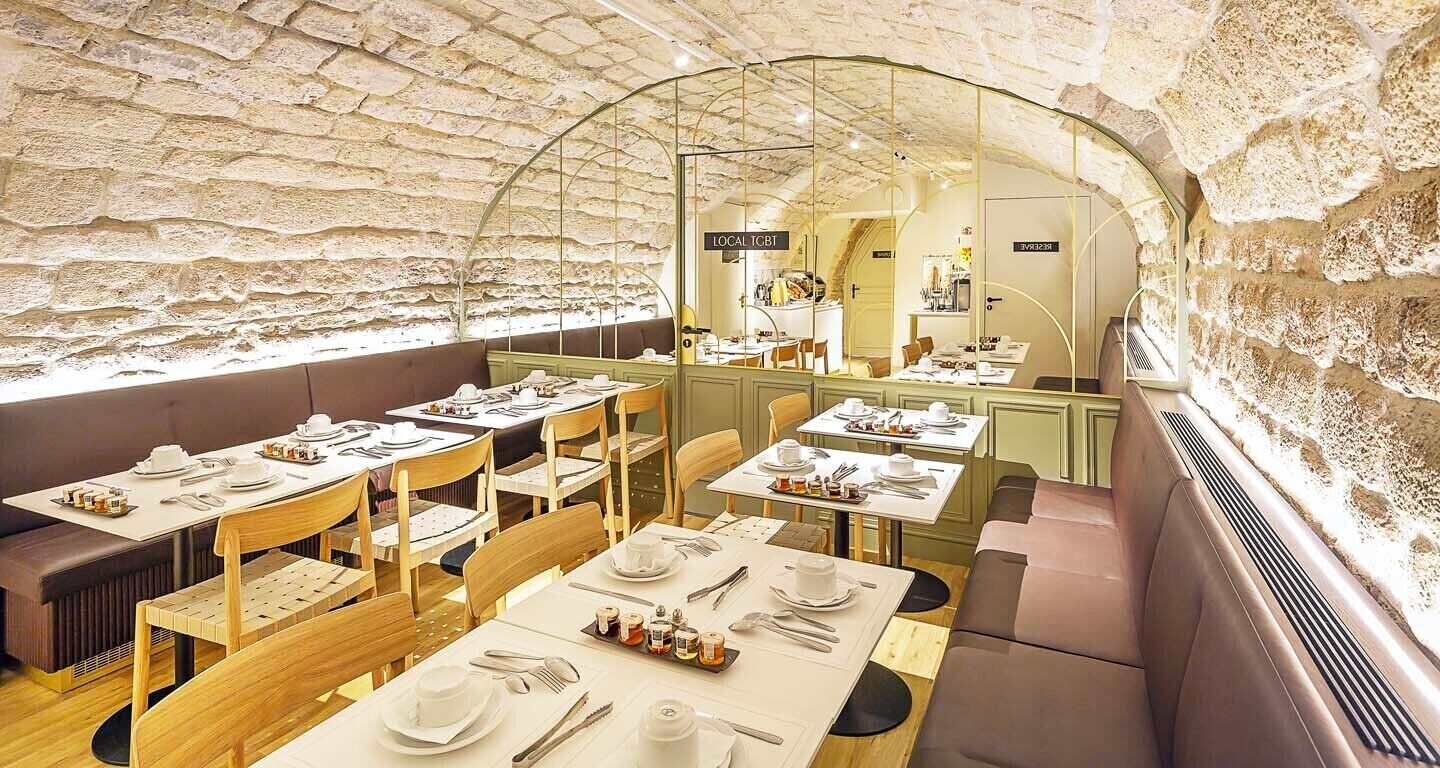 Een restaurant met een rustieke stenen muur en houten meubilair. Tafels zijn gedekt met witte tafelkleden en bestek.