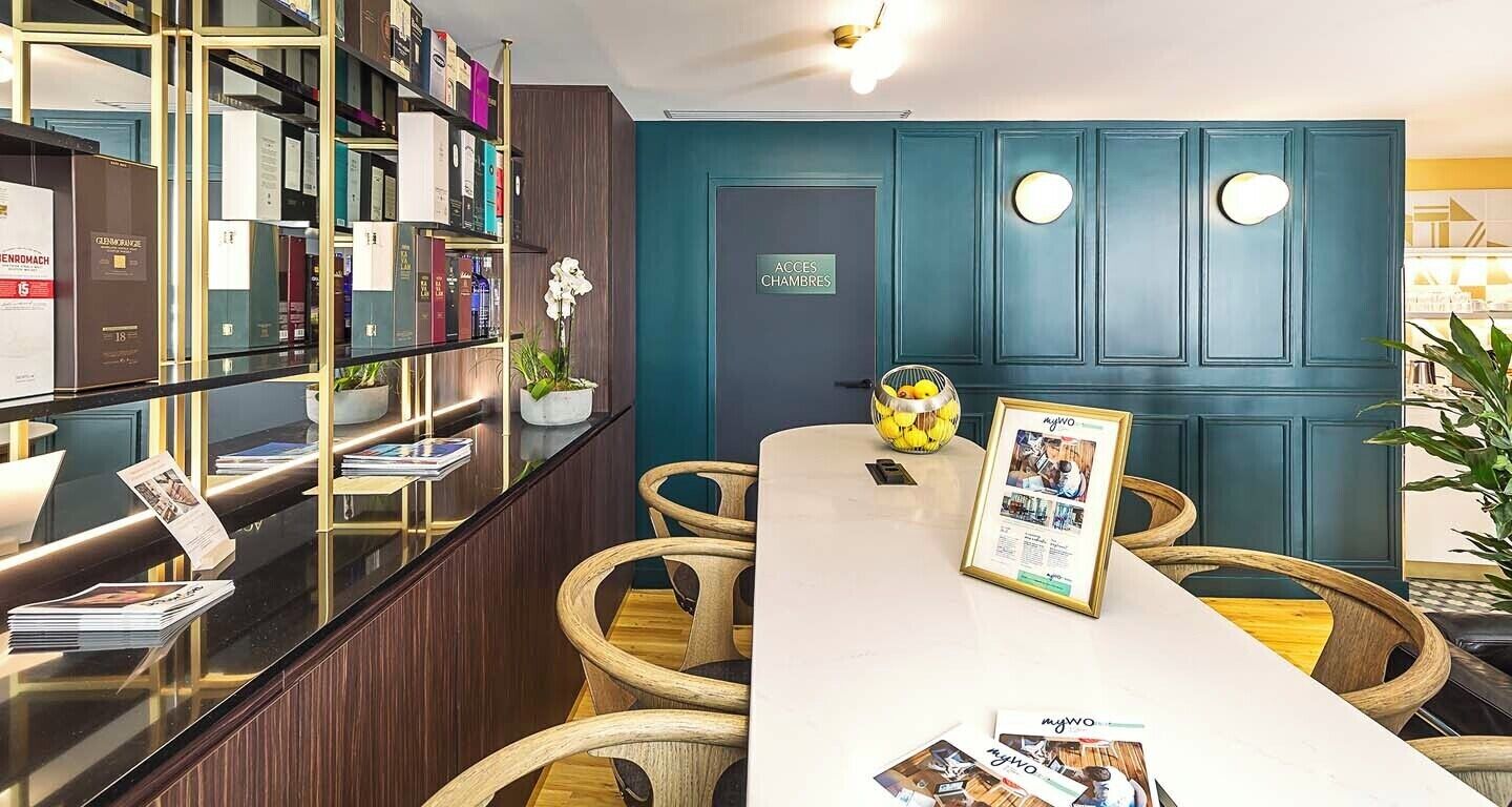 Een receptie met een balie, boekenkasten, een ingelijst foto en rieten stoelen.