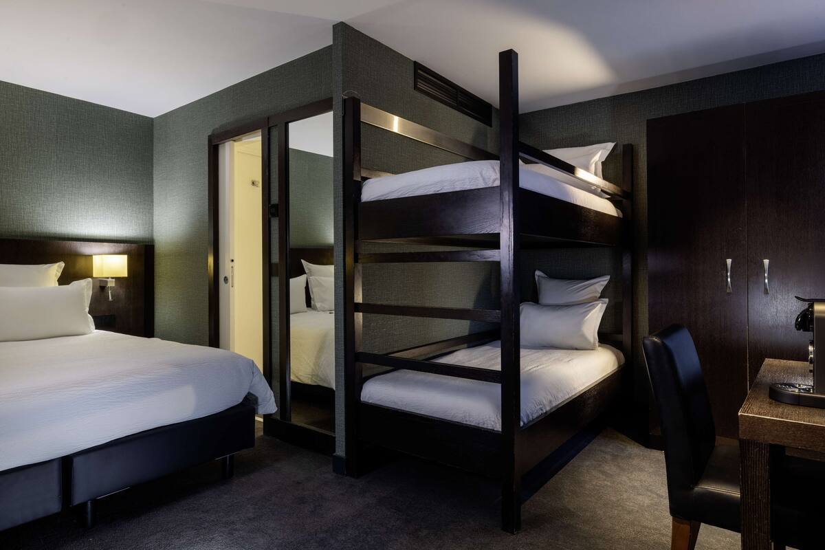 Una habitación de hotel con literas, un escritorio y una silla.