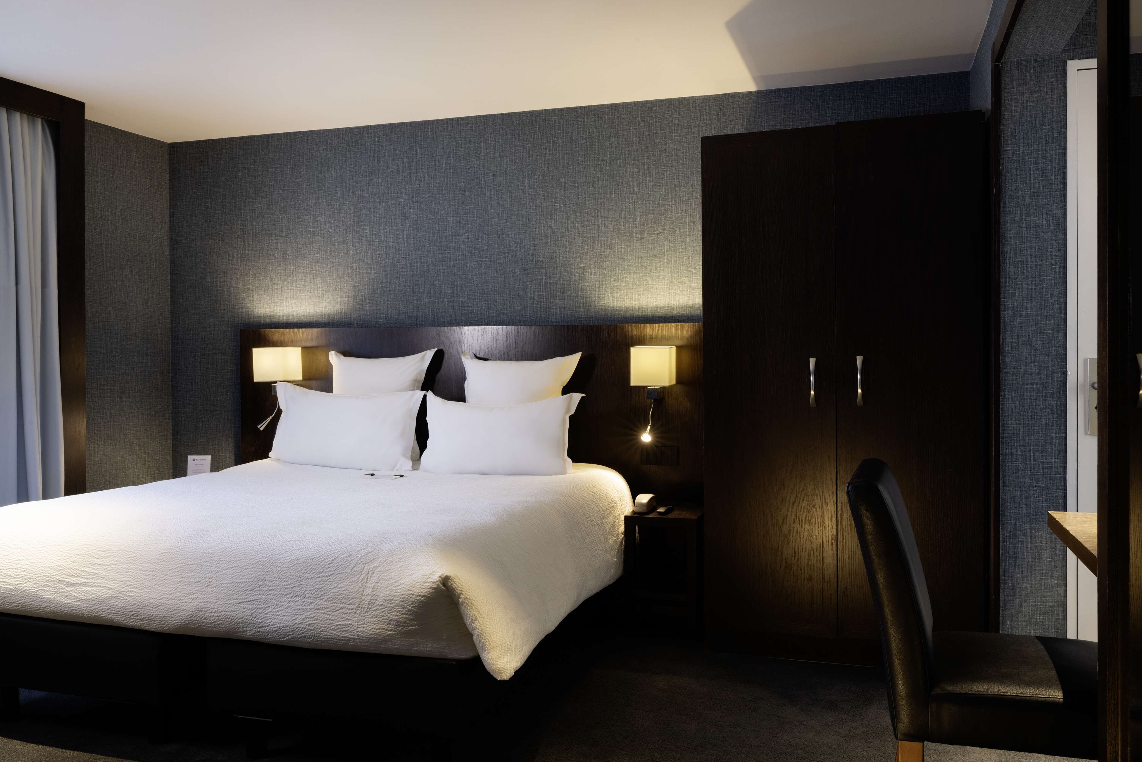 Une chambre d’hôtel avec un grand lit, une table de chevet, un bureau et une armoire.