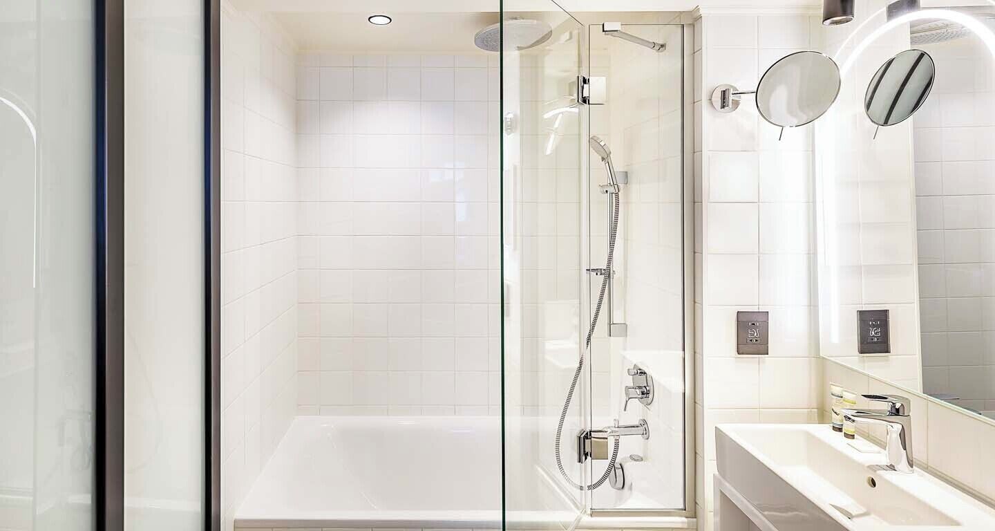 Un baño moderno con ducha envuelta en vidrio, una bañera y un tocador con espejo.