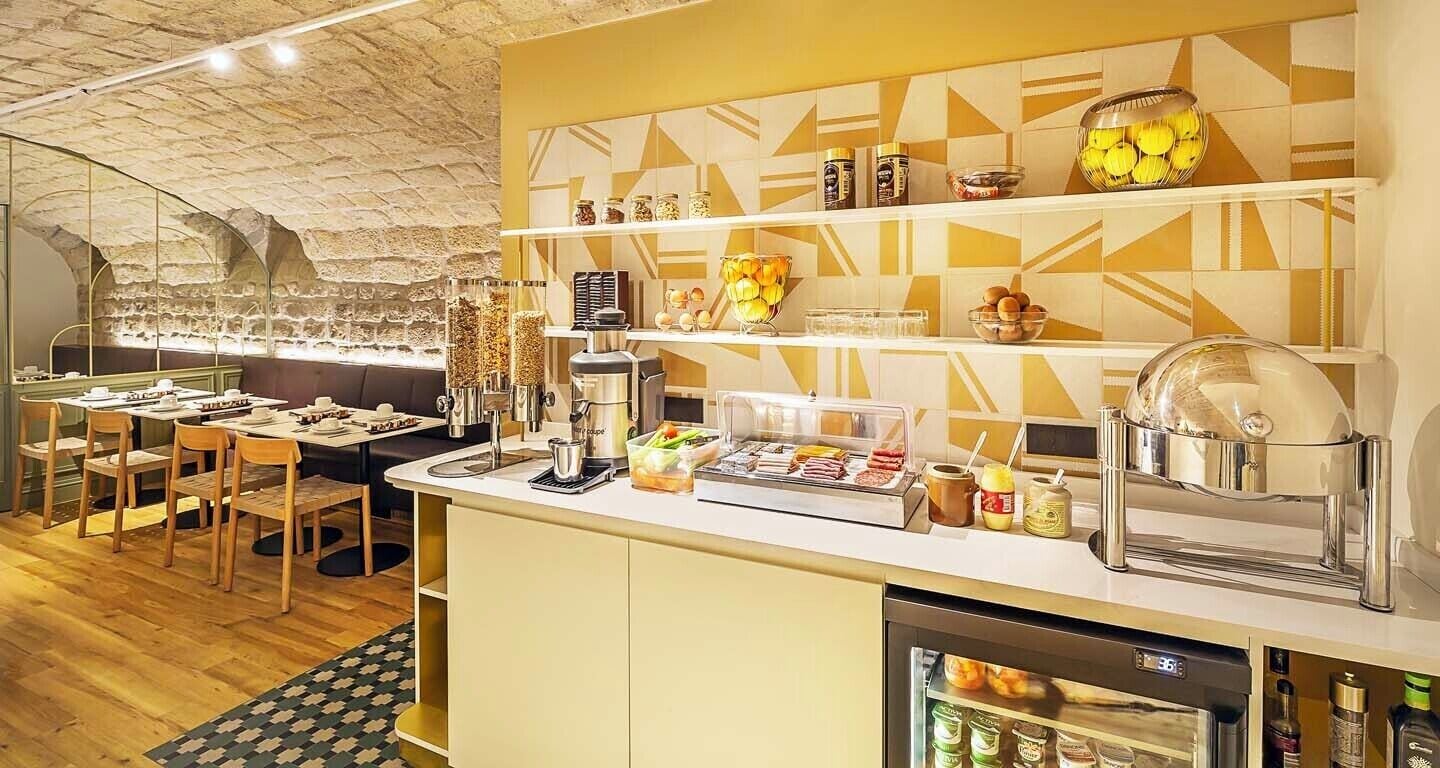 A breakfast bar with seating, a coffee machine, and a refrigerator stocked with beverages.