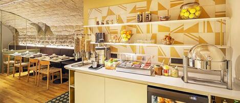 A breakfast bar with seating, a coffee machine, and a refrigerator stocked with beverages.