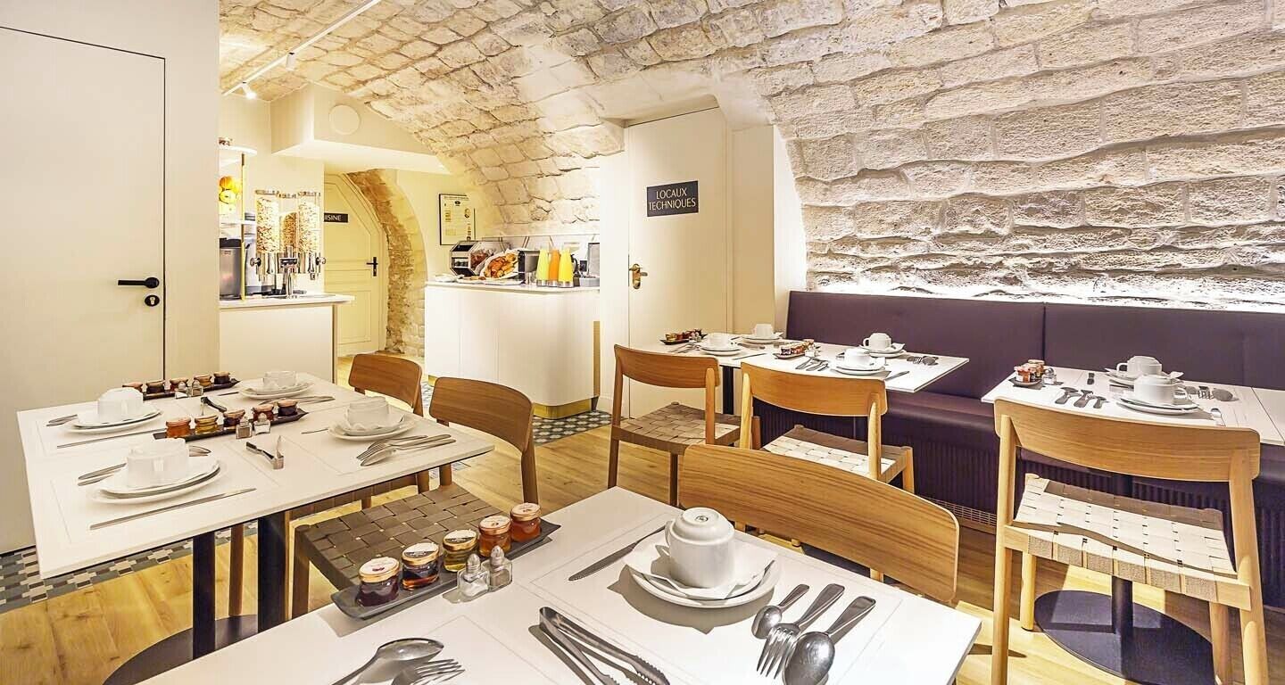 A restaurant with white tables and chairs, a stone wall, and a sign reading "LOCAL TECHNIQUES".