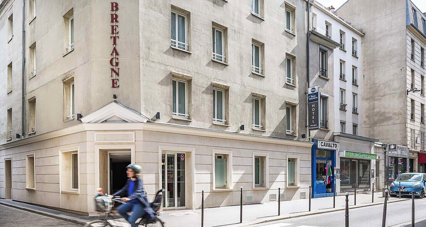 A hotel named "Bretagne" with a classic facade, a visible entrance, and a storefront named "Cavalto" across the street.