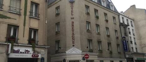 Ein Hotel mit einer klassischen Fassade, mehreren Fenstern und einem Schild, das es als Hotel kennzeichnet.