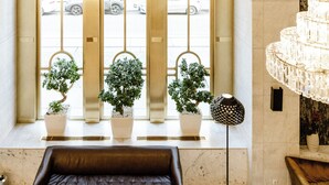 A modern lobby with a large seating area, a chandelier, and potted plants. - Hotel City Central (Vienna)