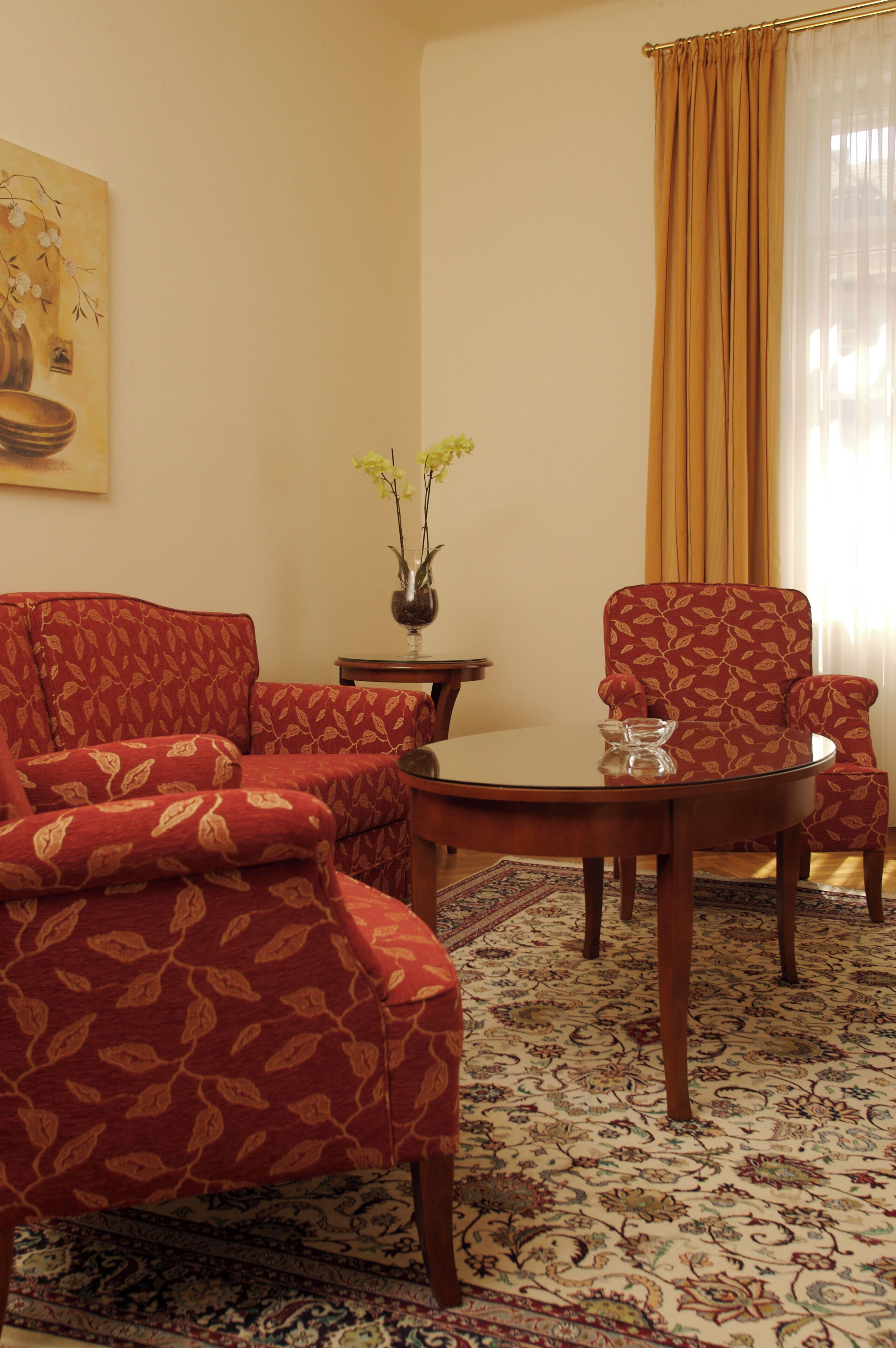 A living room with a sofa, armchair, and a small table with a vase of flowers.