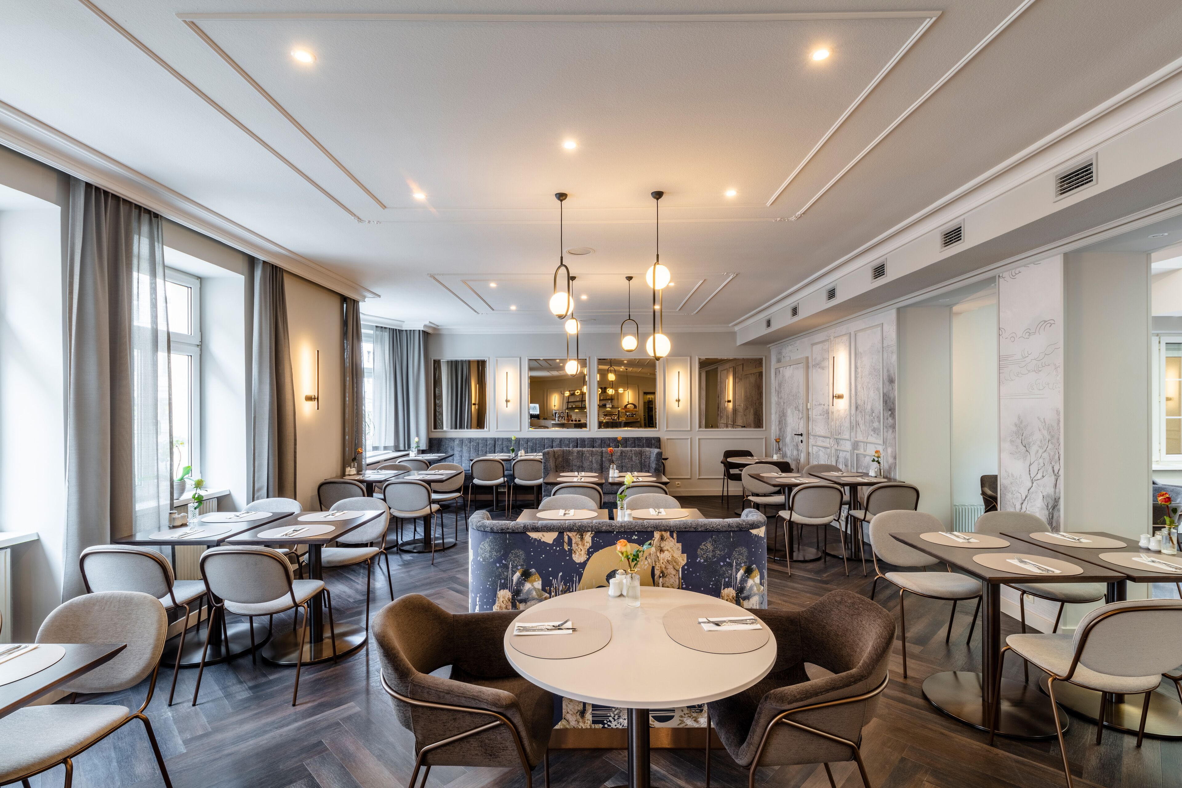 A modern dining area with round tables, chairs, and pendant lighting.