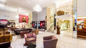 A modern hotel lobby with plush seating, a grand staircase, and a chandelier. - Hotel City Central (Vienna)