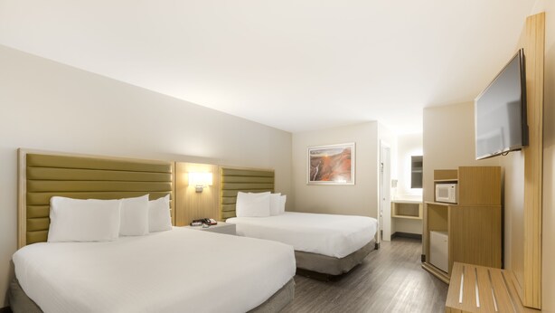 A hotel room with two beds, a flat-screen TV, a microwave, and a small kitchenette. - GreenTree Inn Flagstaff (Flagstaff)