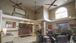 A spacious lobby with multiple seating areas, ceiling fans, and a reception desk. - GreenTree Inn Flagstaff (Flagstaff)