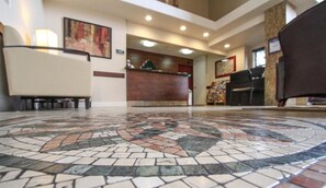 A lobby with a reception desk, a patterned floor, and seating areas.