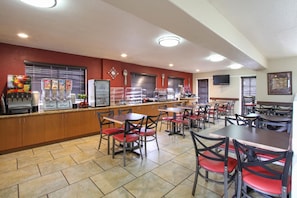 A restaurant with a counter, seating, and a clock on the wall.