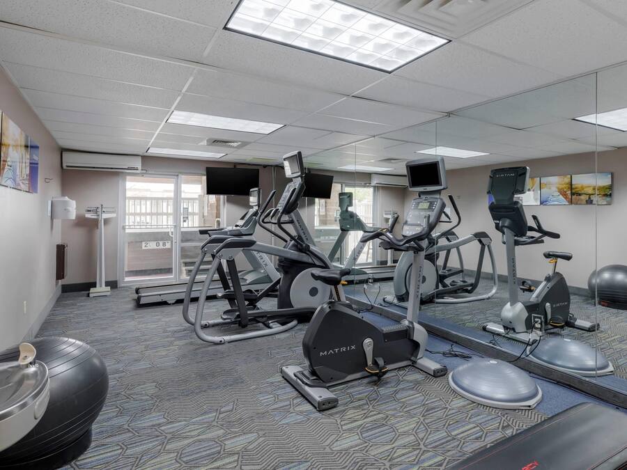 Et fitnesscenter med forskellig træningsudstyr, herunder løbebånd, motionscykler og crosstrainere.