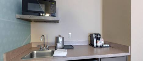 A compact kitchenette with a microwave, coffee maker, and a dishwasher.