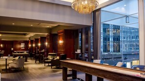 Een moderne hotel lobby met een pooltafel, comfortabele zithoeken en grote ramen met uitzicht op de stad.