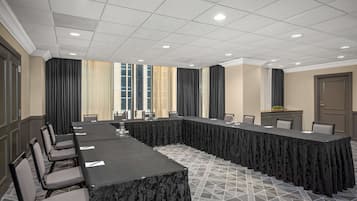 Un salón de conferencias con una mesa larga, sillas y piso de baldosas.