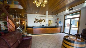 Um saguão de hotel com balcão de recepção, sofá de couro, balcão de madeira e uma janela grande.