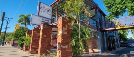 Un motel avec une enseigne indiquant « ELKIRA MOTOEL » et « SALLES DE SOINS, RESTAURANT ».
