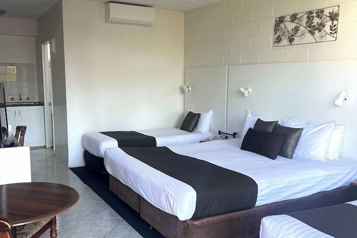 A hotel room with a large bed, a small table, and a chair.
