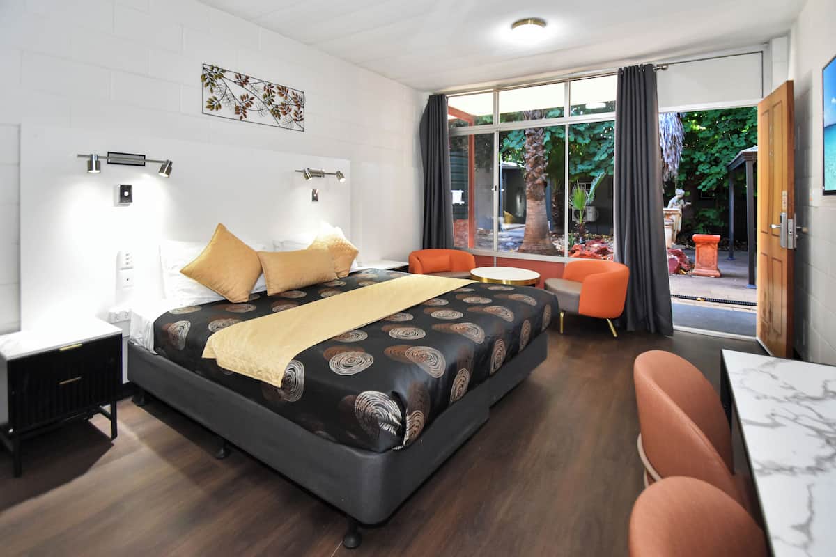 A hotel room with a bed, a desk, a chair, and a small table.