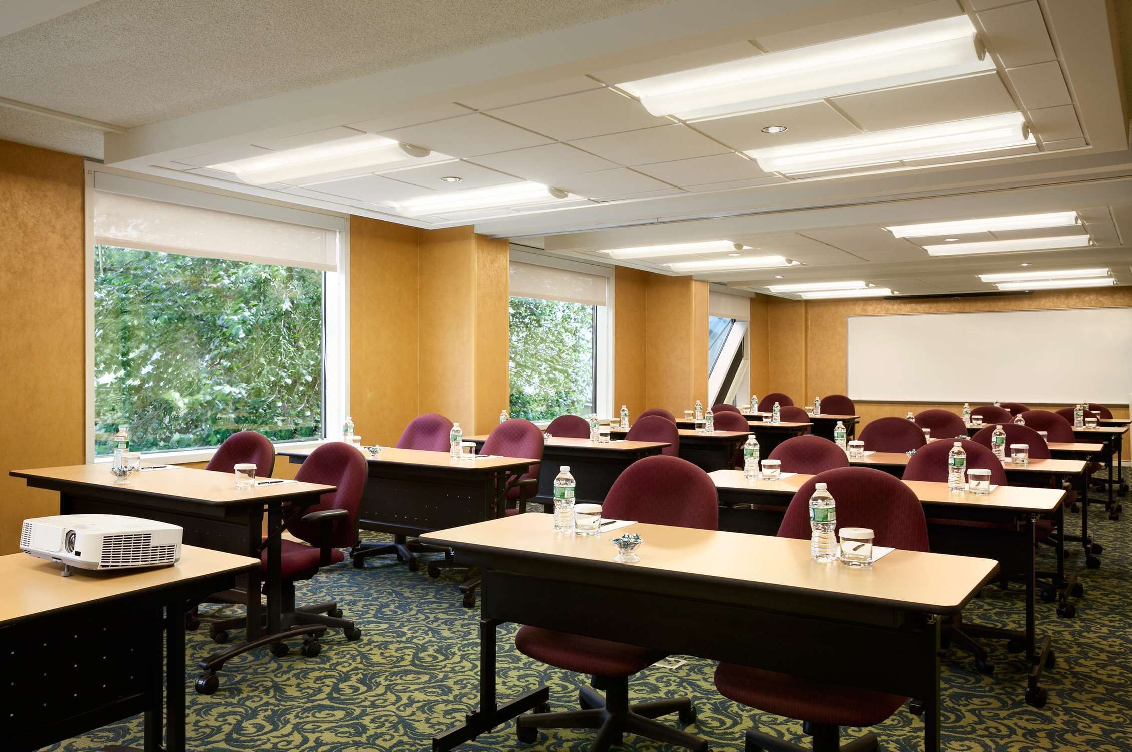 A conference room with rows of tables, chairs, and a projector.