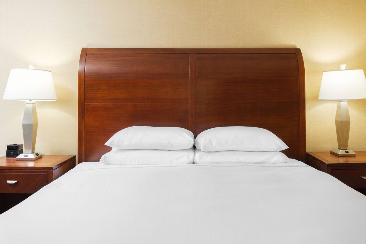Ein Hotelzimmer mit einem großen Bett, zwei Nachttischen und jeweils einer Lampe.