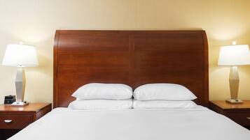 A hotel room with a large bed, two bedside tables, and two lamps.