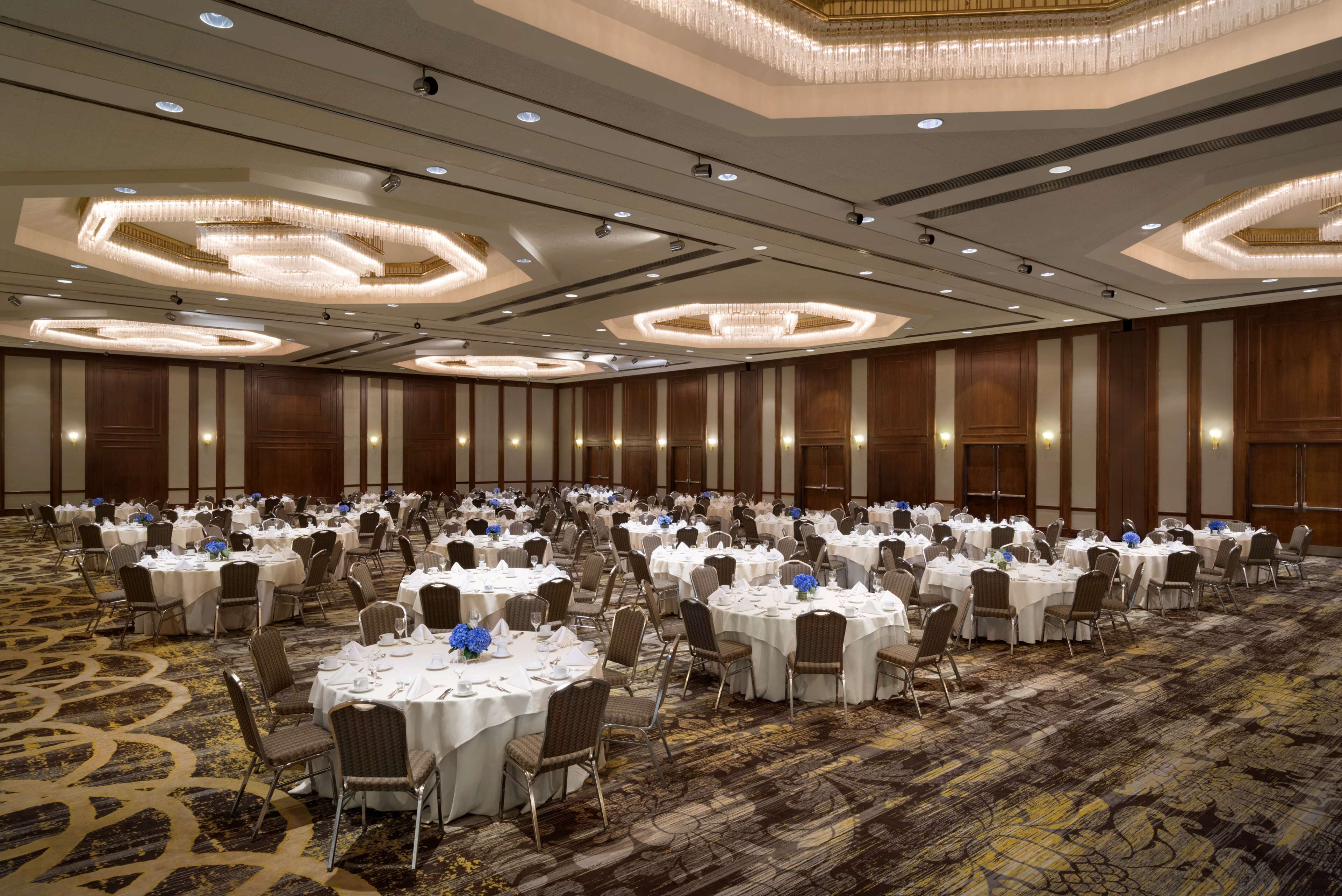 A large banquet hall with round tables set for dining, equipped with chairs and table settings.