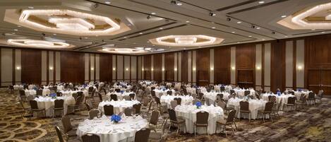A large banquet hall with round tables set for dining, equipped with chairs and table settings.