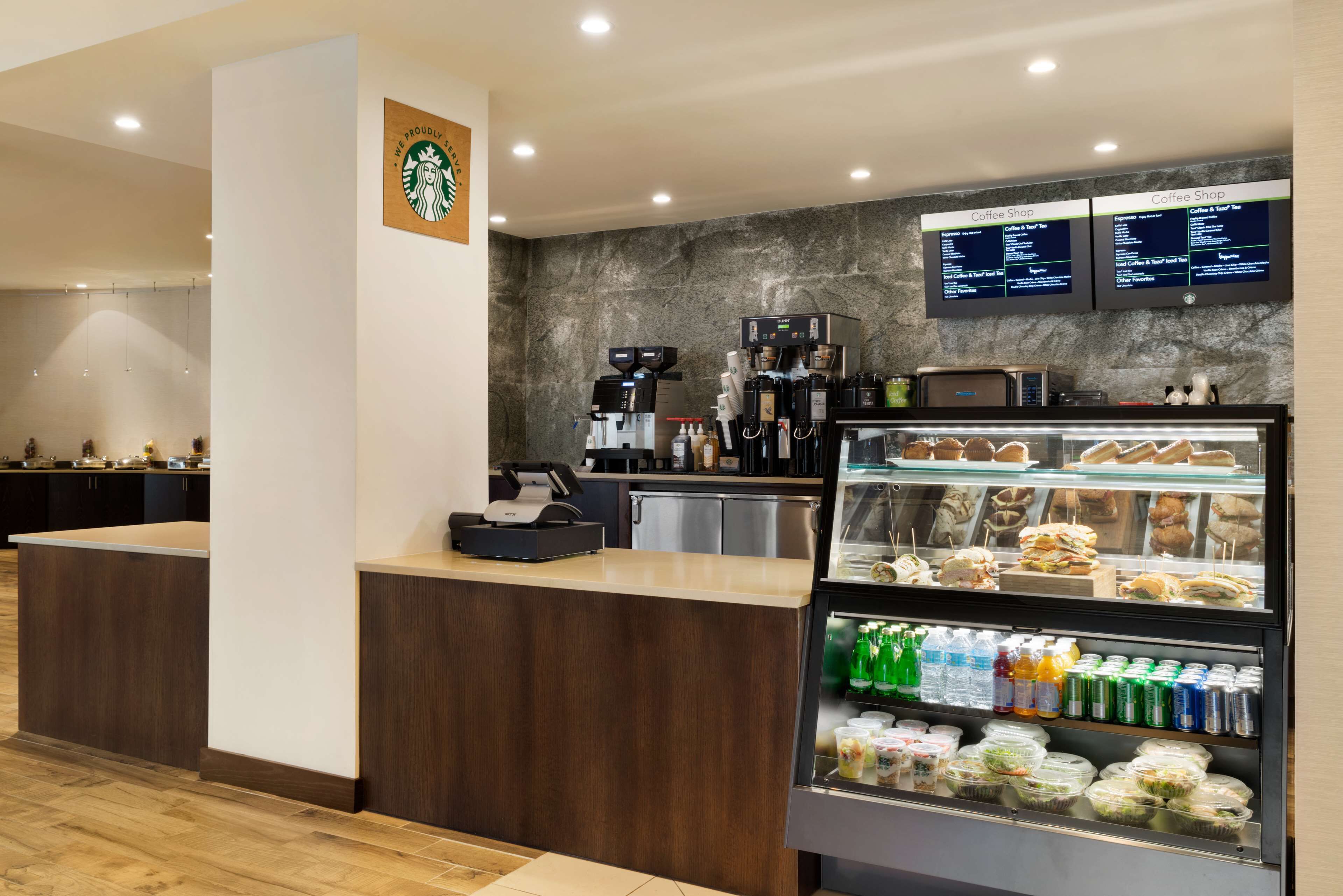 Una caffetteria Starbucks con un bancone, bacheche con il menù e una vetrina con dolci e bevande.