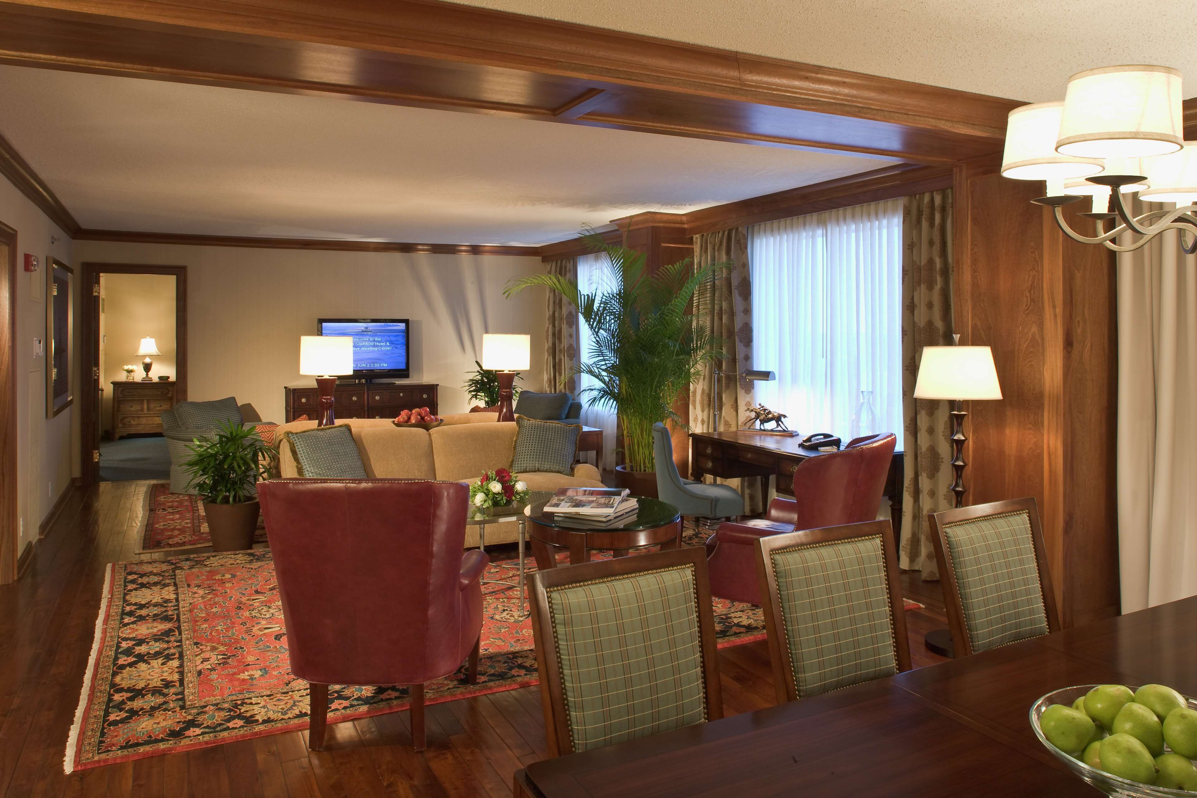 A hotel room with a living area, dining table, and a television.