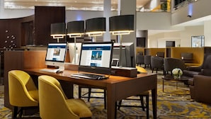 Eine moderne Hotelhalle mit zwei Computerarbeitsplätzen, einer Rezeption und Sitzbereichen.